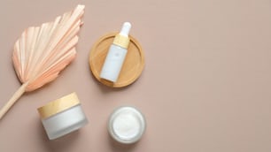 Natural cosmetics set and dry flower on pastel beige background. Organic skincare beauty products. Flat lay, top view.