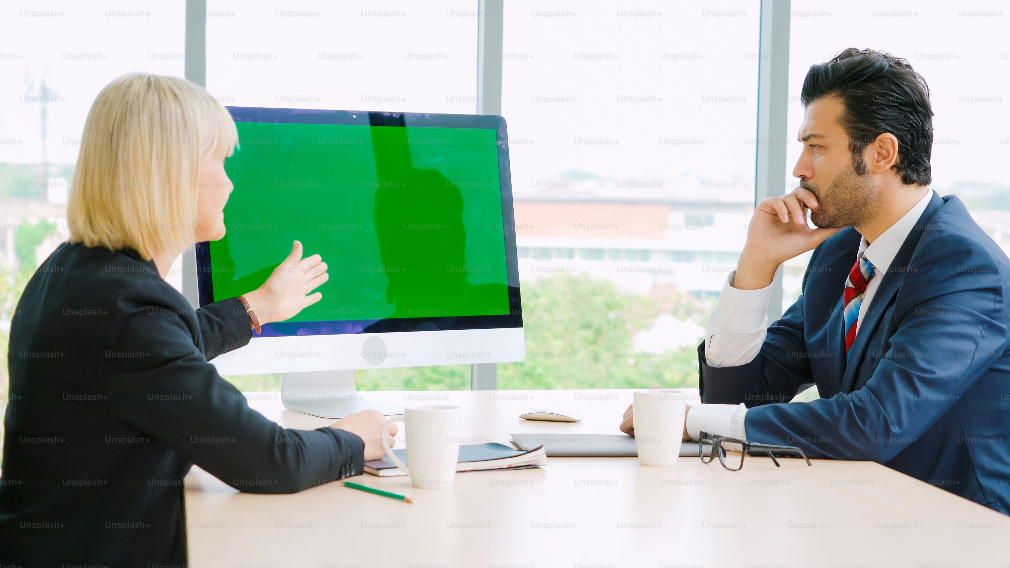 Business people in the conference room with green screen chroma key TV or computer on the office table. Diverse group of businessman and businesswoman in meeting on video conference call .