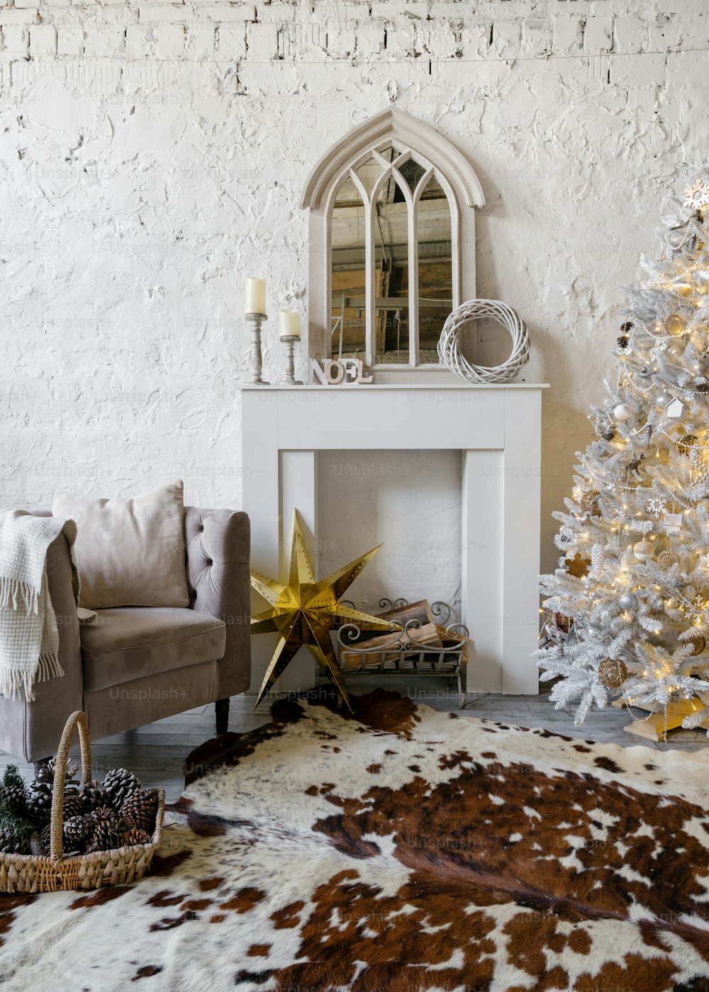 Vertical photo of decorated living room with decorative fireplace, comfort armchair and cow leather carpet on floor. Christmas tree with new year decor in cozy room