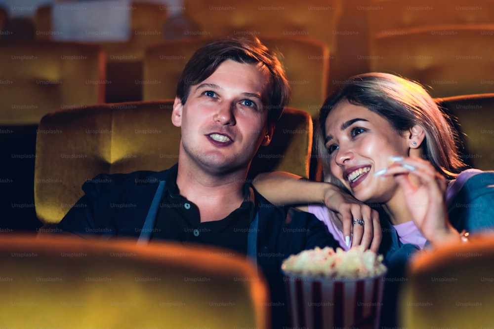 Amante caucasiano gostando de assistir filme e comendo pipoca juntos no cinema