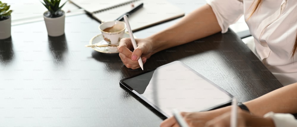 Captura recortada de una mujer de negocios sostiene un lápiz óptico escribiendo en una tableta de pantalla vacía.
