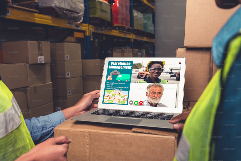 Warehouse staff talking on video call at computer screen in storage warehouse . Online software technology connects people working in logistic factory by virtual conference call on internet network .