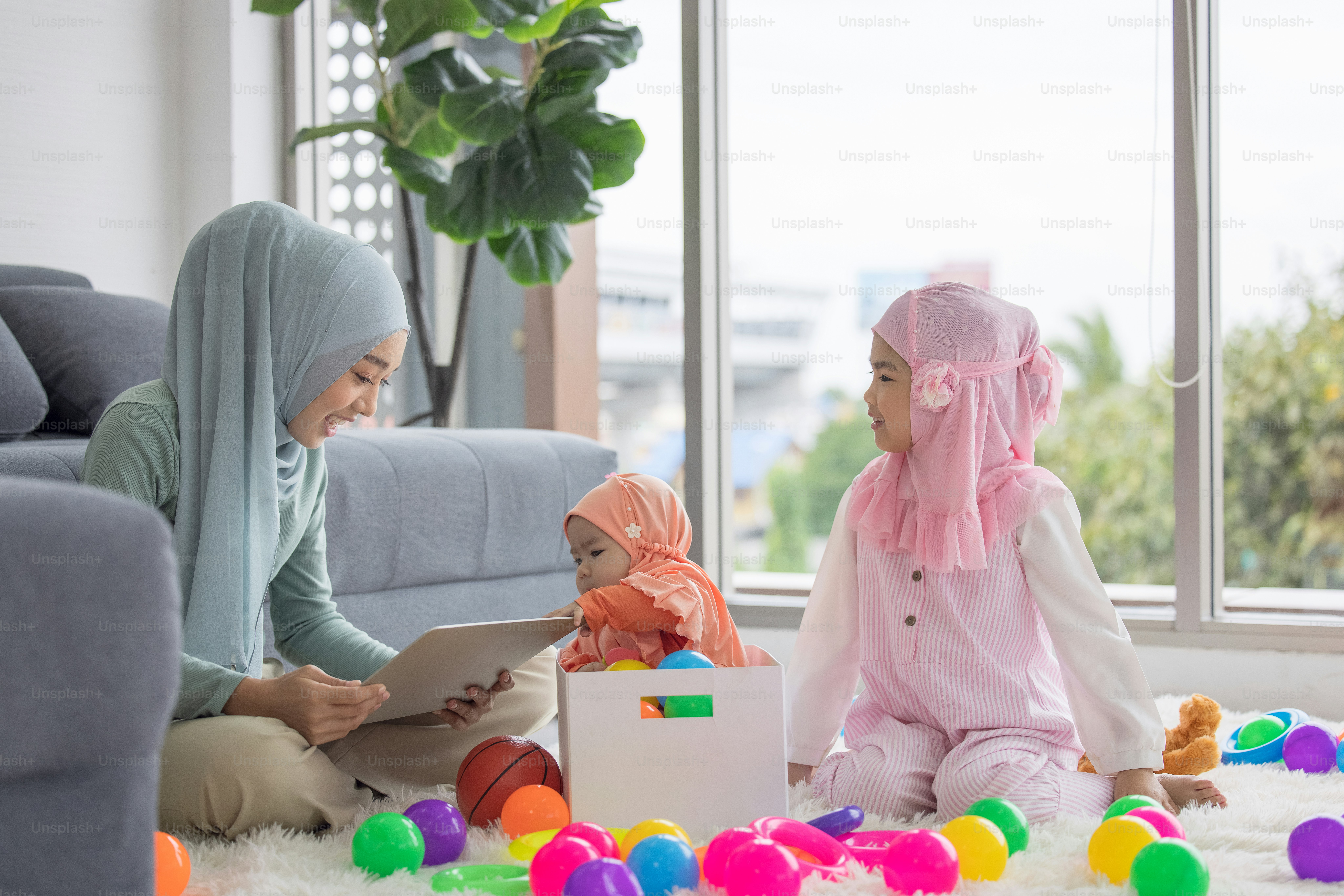 Muslim Mother working with laptop and Cute little baby playing toys in living room at home.