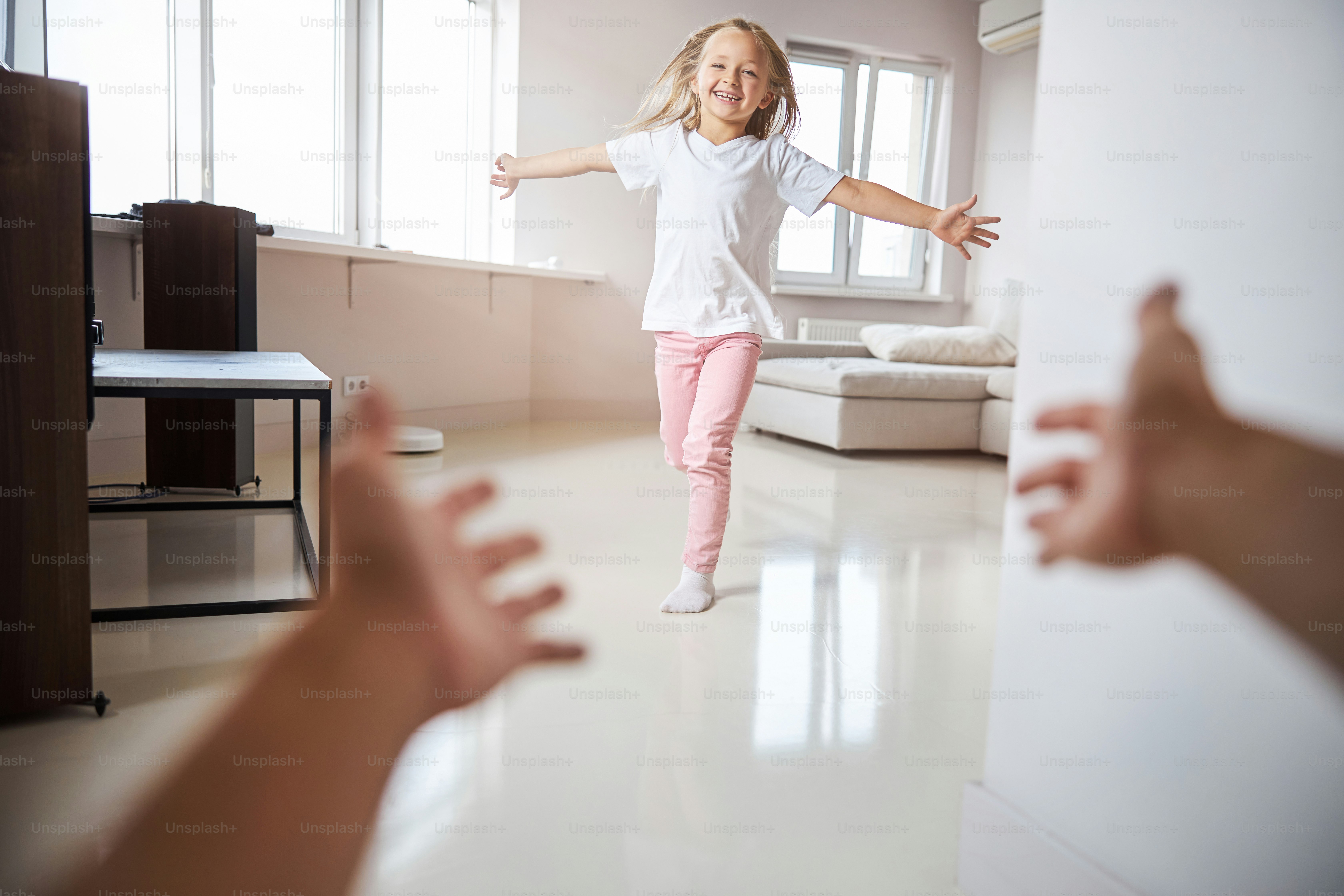 Full length portrait of charming cute girl running to the hug in the big modern apartment