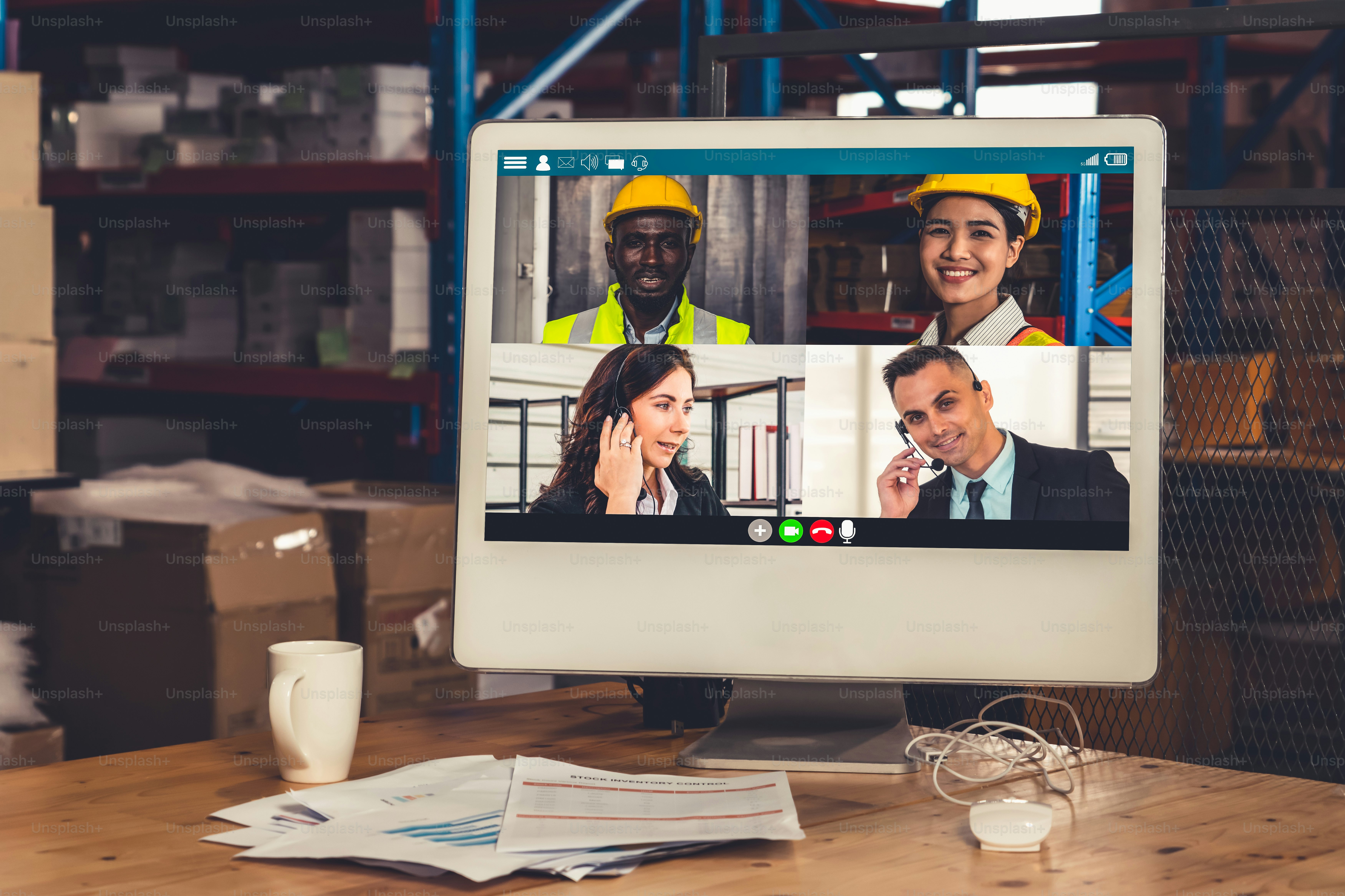 Warehouse staff talking on video call at computer screen in storage ...