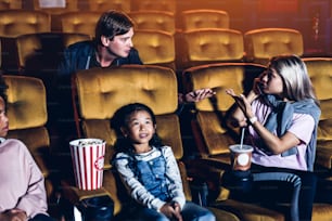 Caucasian woman talking on phone in the cinema and showing a rude gesture at the man behind her