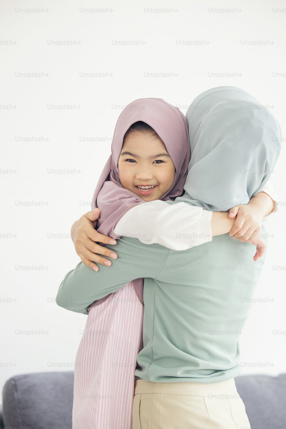 Retrato de la feliz y encantadora familia árabe musulmana madre abraza a la pequeña hija sonriendo
