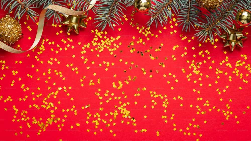 Christmas frame border. Fir tree branches and Xmas decorations on red background with golden confetti. Christmas card mockup, New Year banner design template.
