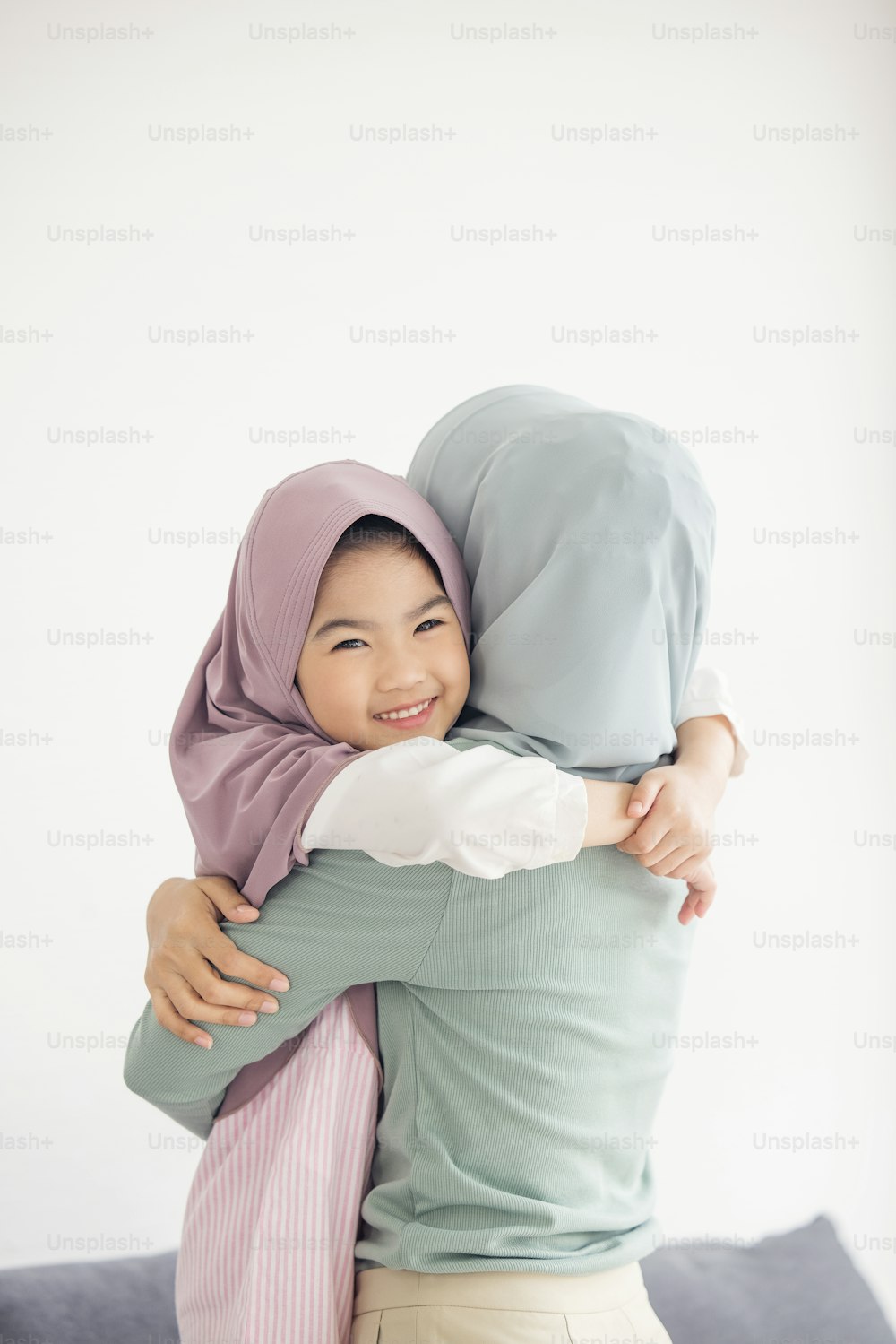Retrato de la feliz y encantadora familia árabe musulmana madre abraza a la pequeña hija sonriendo