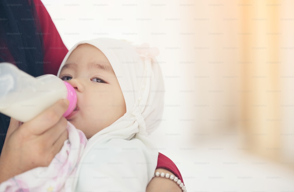 아기에게 우유 한 병을 먹이는 무슬림 어머니.