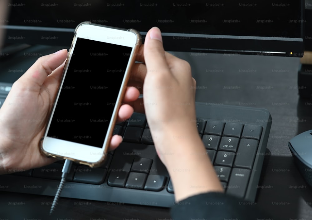Close up da mulher usando o telefone inteligente móvel em seu espaço de trabalho no escritório.
