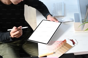 Die beschnittene Aufnahme eines jungen männlichen Grafikdesigners arbeitet mit interaktivem Stift und einem digitalen Tablet mit leerem Bildschirm in der Workstation.