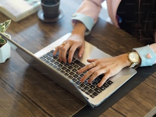 Draufsicht der weiblichen Handeingabe auf der Laptop-Tastatur auf dem Holztisch