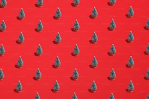 Pattern background of green Christmas trees on red. Xmas, New Year, winter holidays concept. Flat lay, top view.