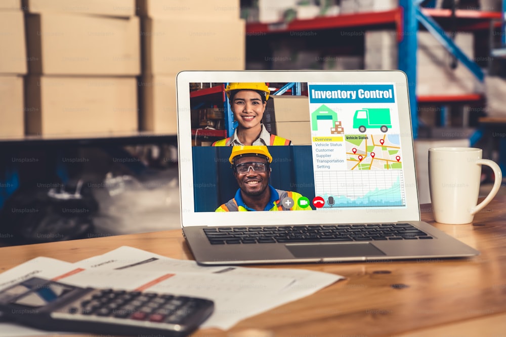 Warehouse staff talking on video call at computer screen in storage warehouse . Online software technology connects people working in logistic factory by virtual conference call on internet network .