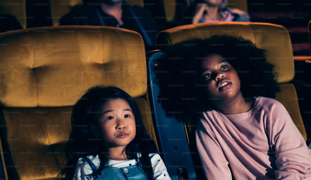 Three children having fun and enjoy watching movie in cinema