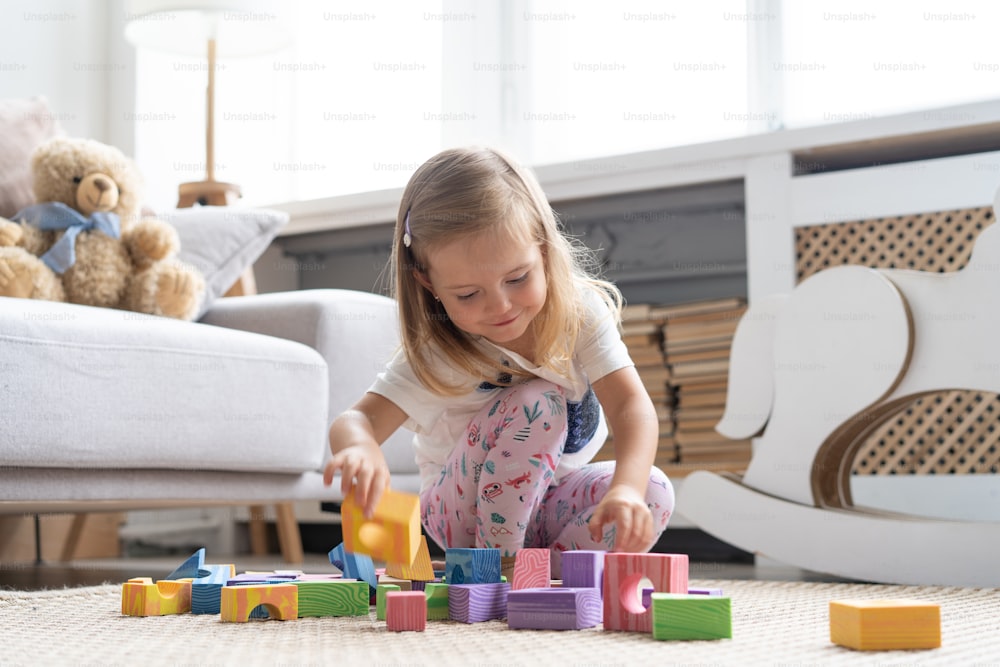 Little cute girl playing block toys in playroom at home