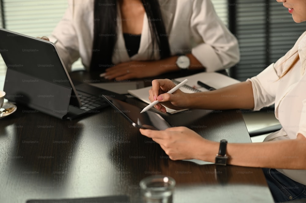 Cropped shot of two businesswoman are using a digital tablet to discuss information in meeting room.