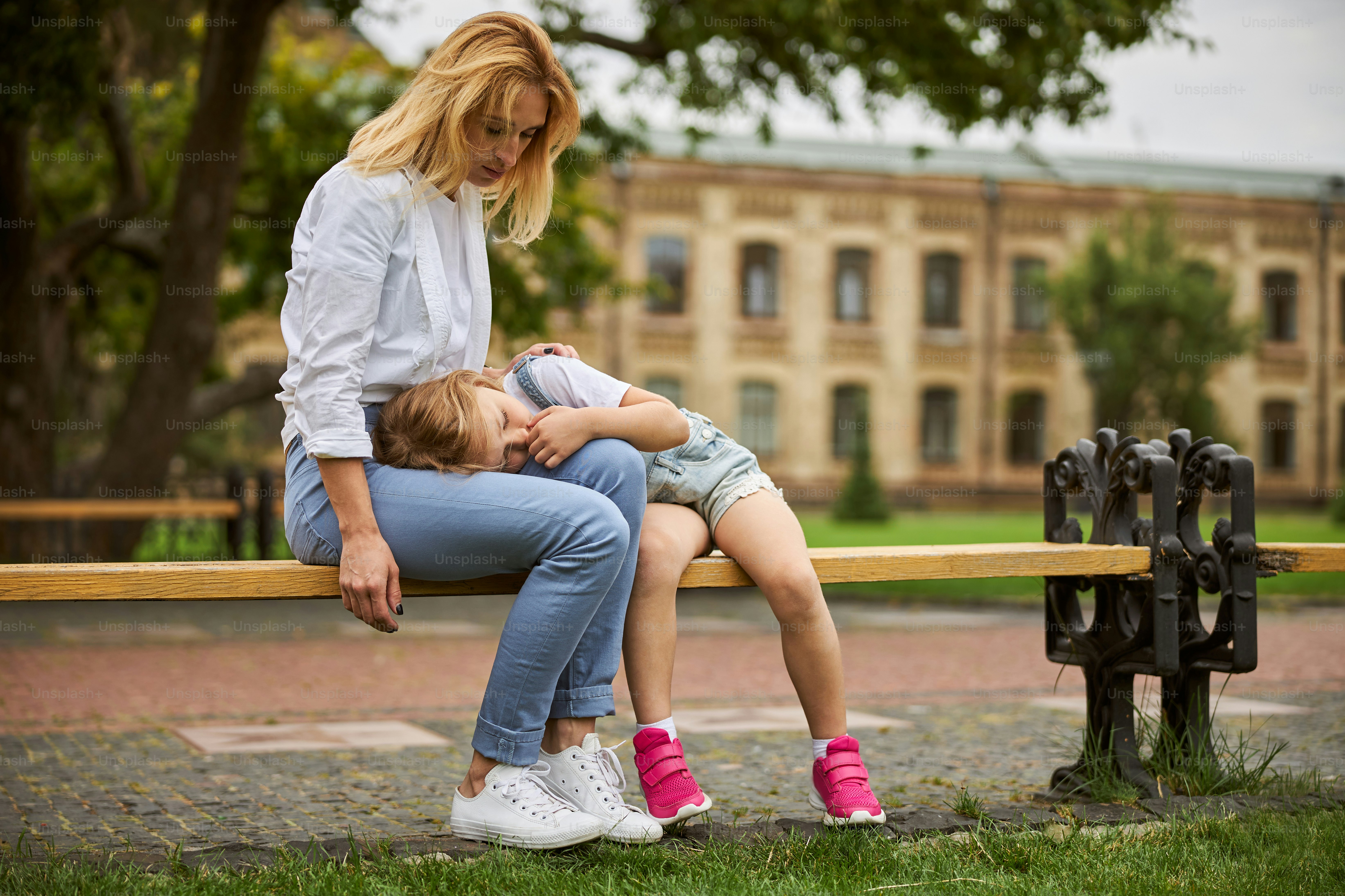 Porträt einer gut aussehenden Frau, die auf ihre Tochter aufmerksam macht, während sie Zeit im Stadtpark verbringt