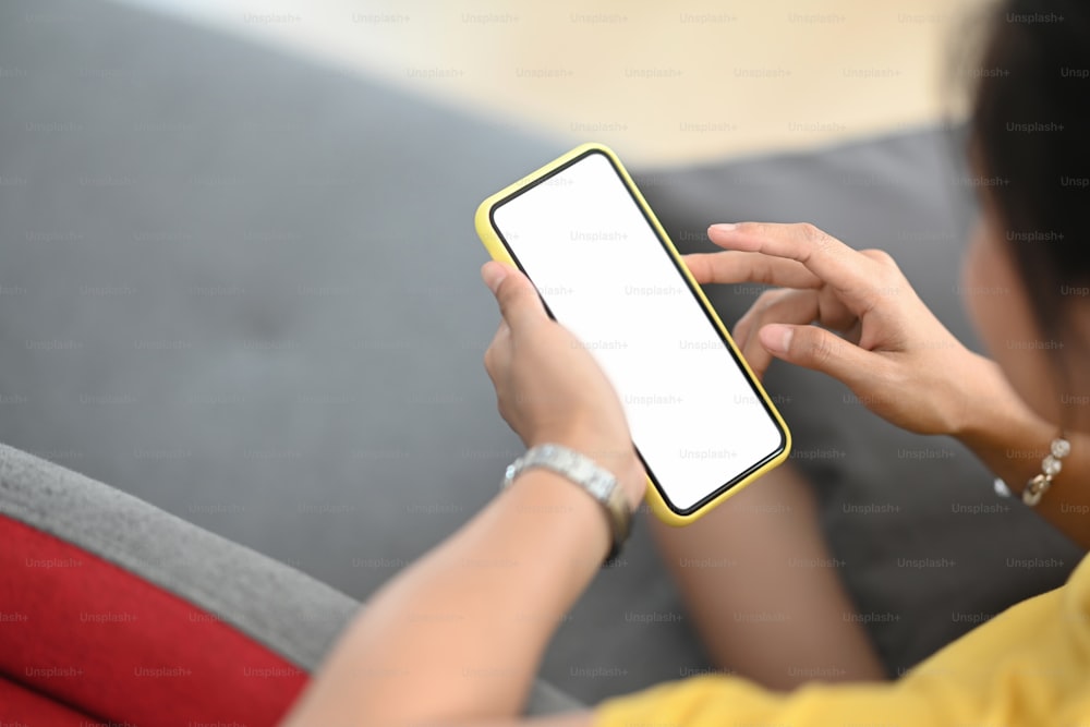 グラフィックディスプレイモンタージュ用の空白の白い画面で携帯電話を保持している女性の手の接写。