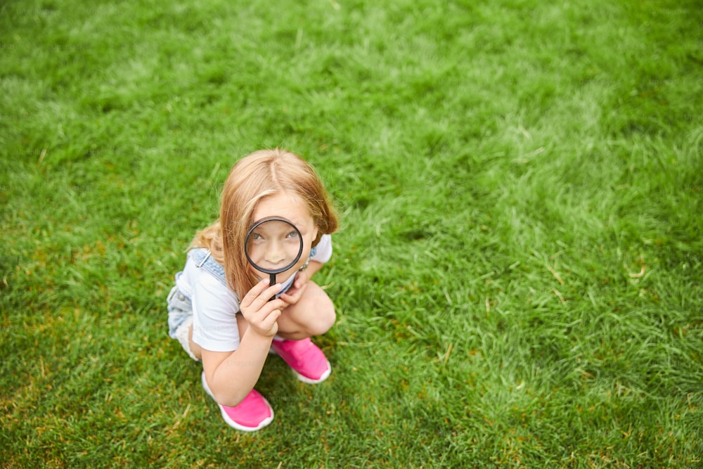 Full length portrait of female child with loupe learning nature outside