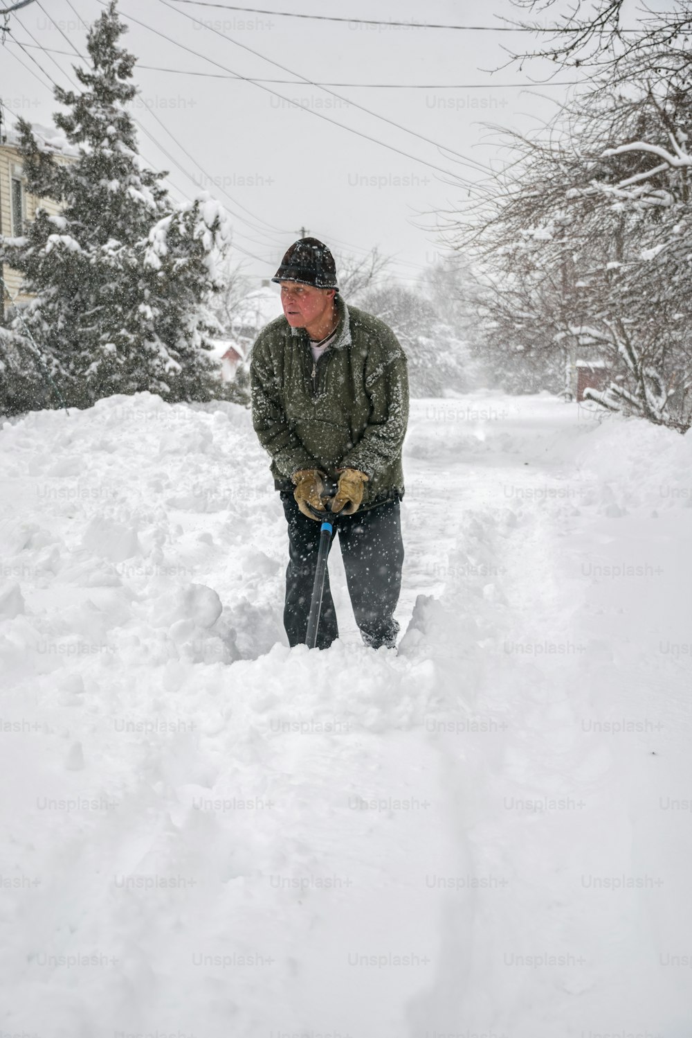 elderly man with a shovel in his hands clears the street after a heavy snowfall. Man at seasonal work