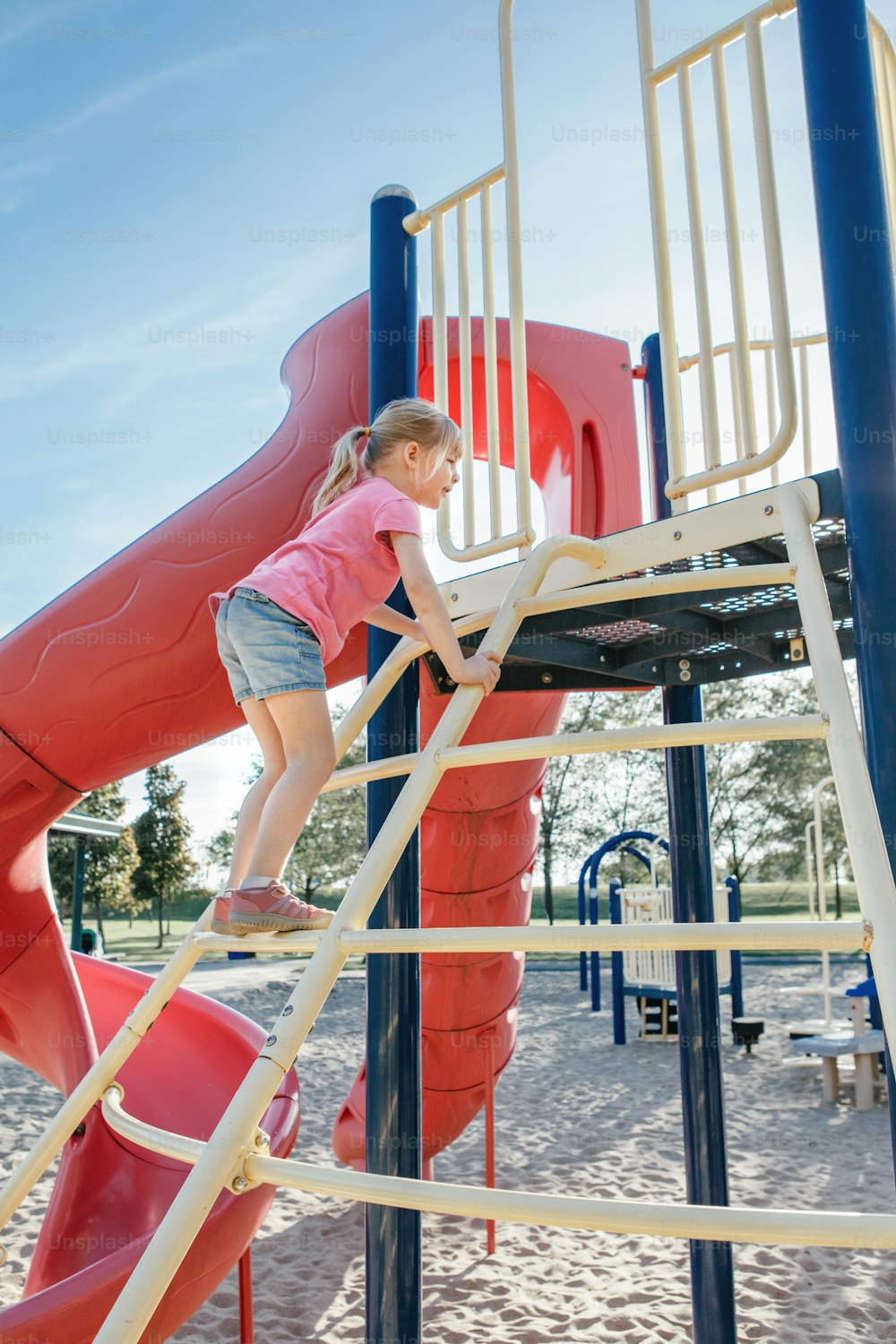 Active happy brave Caucasian girl child climbing staircase climber on playground schoolyard outdoor on summer sunny day. Seasonal kids activity outside. Authentic childhood lifestyle concept.
