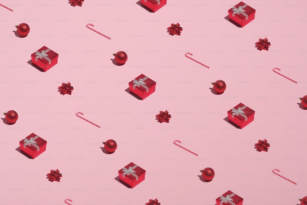Christmas pattern made of red gift boxes, candy canes, decorations, balls on pink background. Christmas New Year, winter holidays concept.