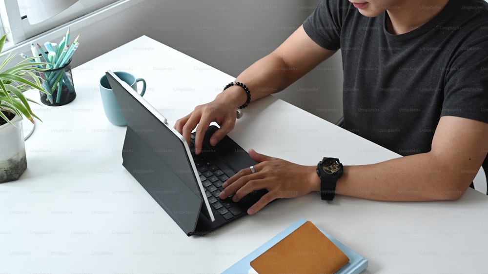 Cropped shot of a concentrated freelancer man is working on a computer tablet while sitting at the table at home.