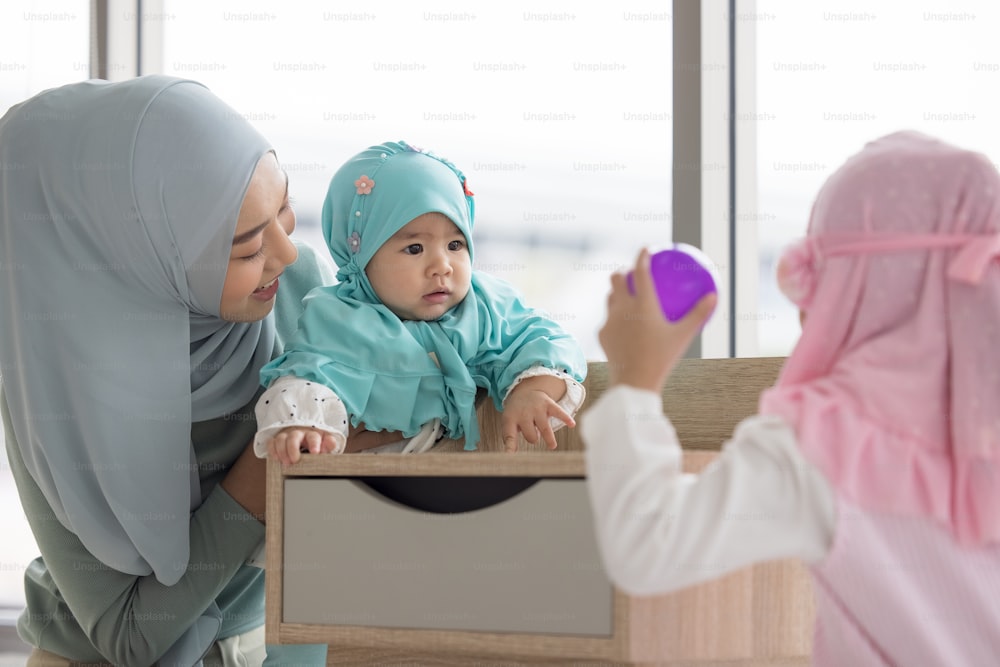 Una madre musulmana con hiyab es su hija pequeña sentada en la sala de estar, Relación amorosa