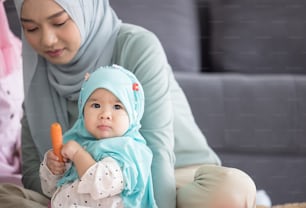 Mãe muçulmana em hijab é sua filhinha sentada na sala de estar, Relacionamento Amoroso