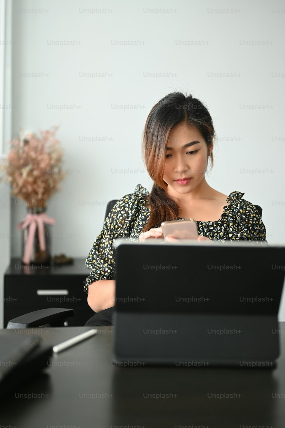 Portrait of a confident businesswoman sitting in workspace and working on computer tablet.