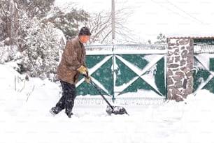 elderly man with a shovel in his hands clears the street after a heavy snowfall. Man at seasonal work