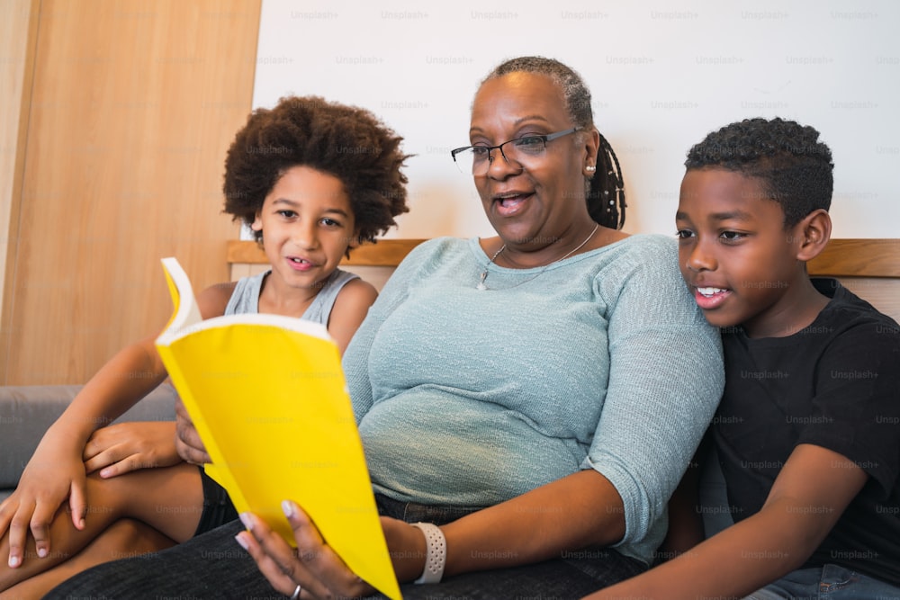 Portrait of African American grandmother reading a book to her grandchildren at home. Family concept.