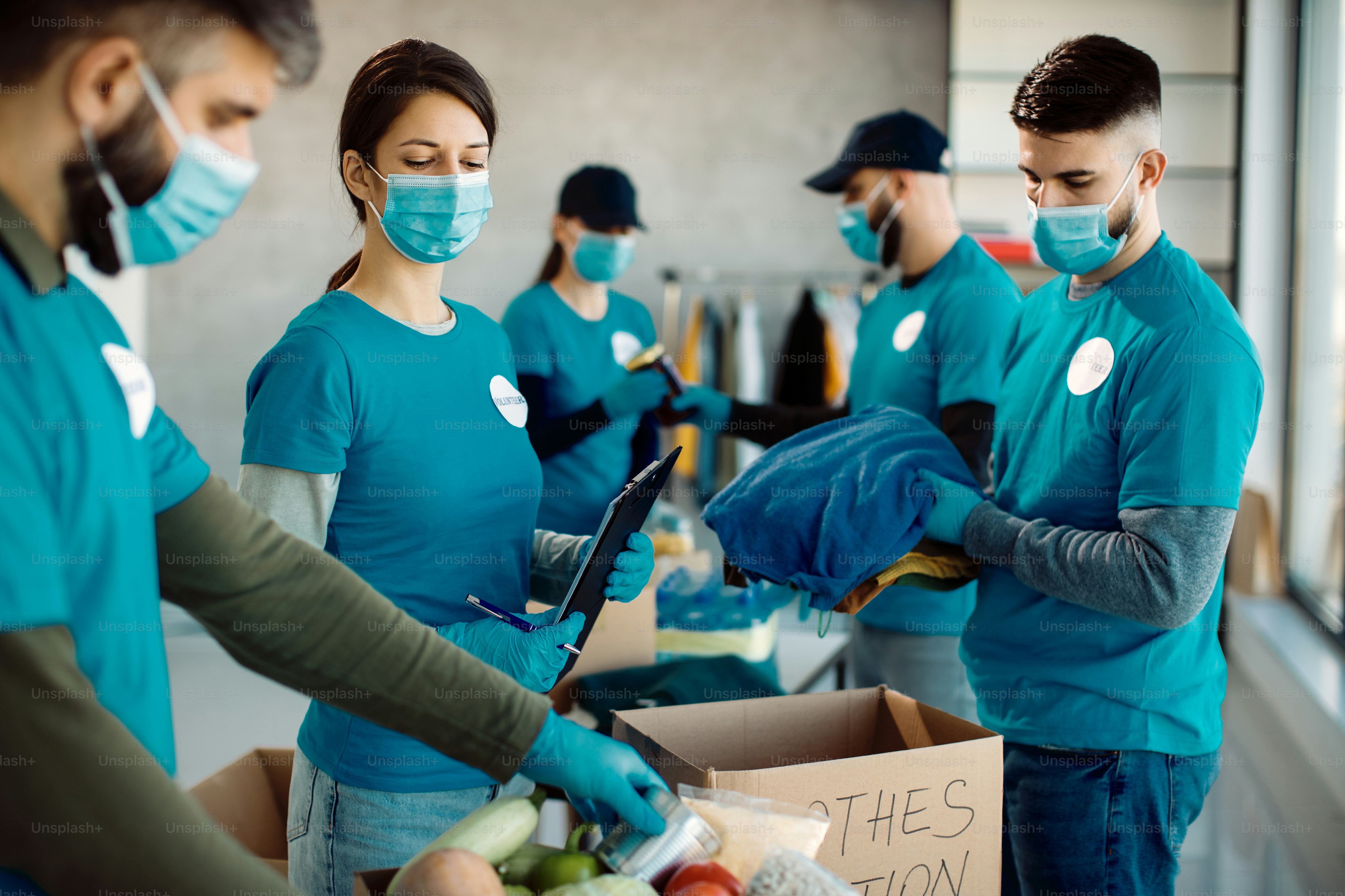 Group of volunteers wearing protective face masks while packing food ...