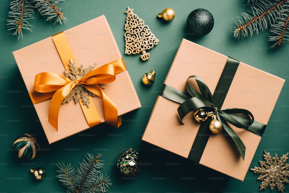 빈티지 크리스마스 플랫 레이 구성. 리본 활, 공, 짙은 녹색 배경에 전나무 가지가 있는 복고풍 선물 상자. 크리스마스 선물, 새해 놀라움 개념.