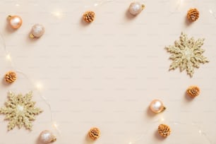 エレガントなクリスマスフラットレイ構図。パステルベージュの背景に金色の雪片、ボール、コーン、花輪。ミニマルな北欧スタイル。クリスマスグリーティングカードのモックアップ。