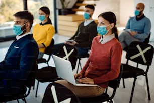 Female entrepreneur using laptop while being on a business seminar during coronavirus pandemic.