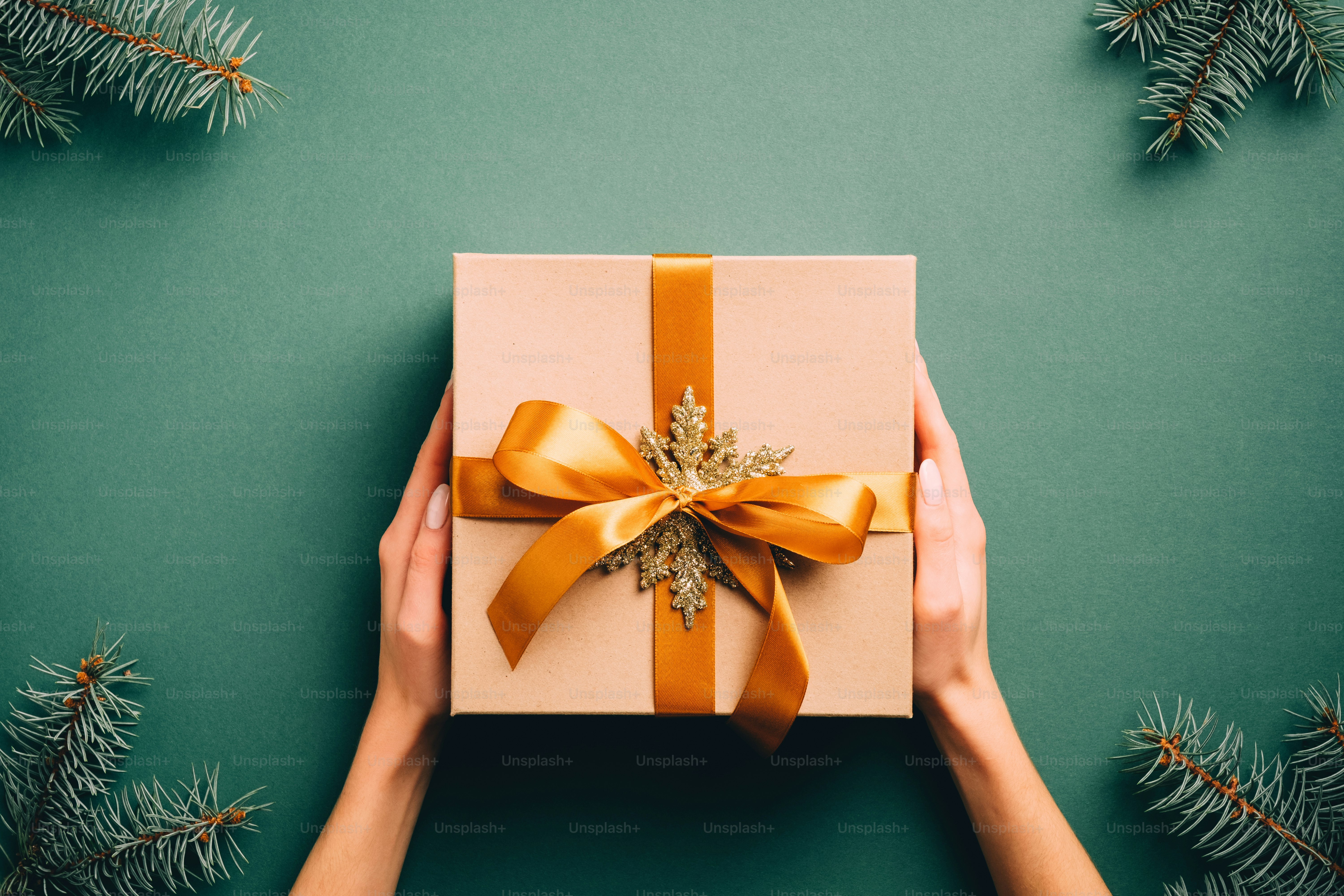 Boîte-cadeau de Noël vintage avec noeud de ruban doré et flocon de neige sur fond vert foncé avec des branches de sapin. Cadeau de Noël de style rétro, surprise du Nouvel An.