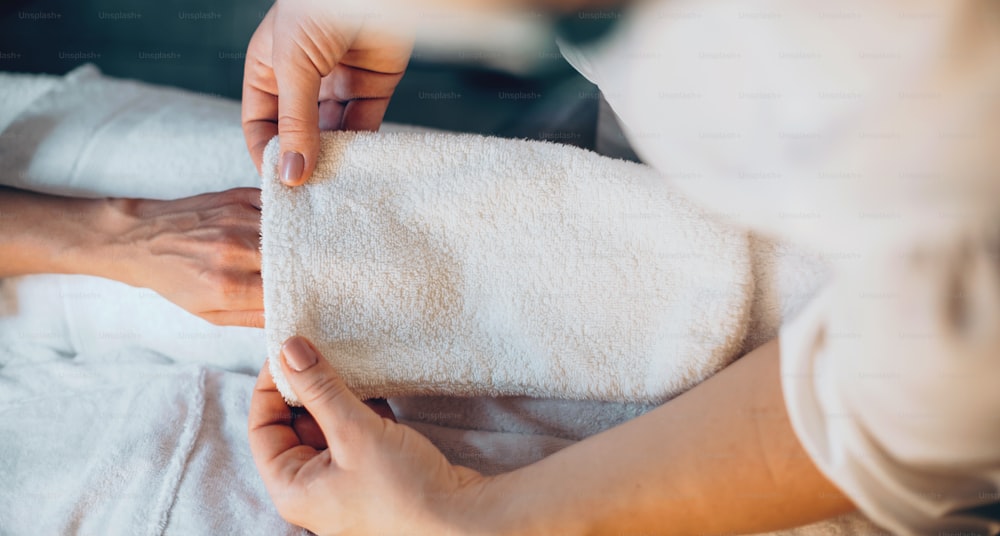Massagista caucasiano está secando a mão do cliente após a sessão de massagem nas mãos no salão de spa