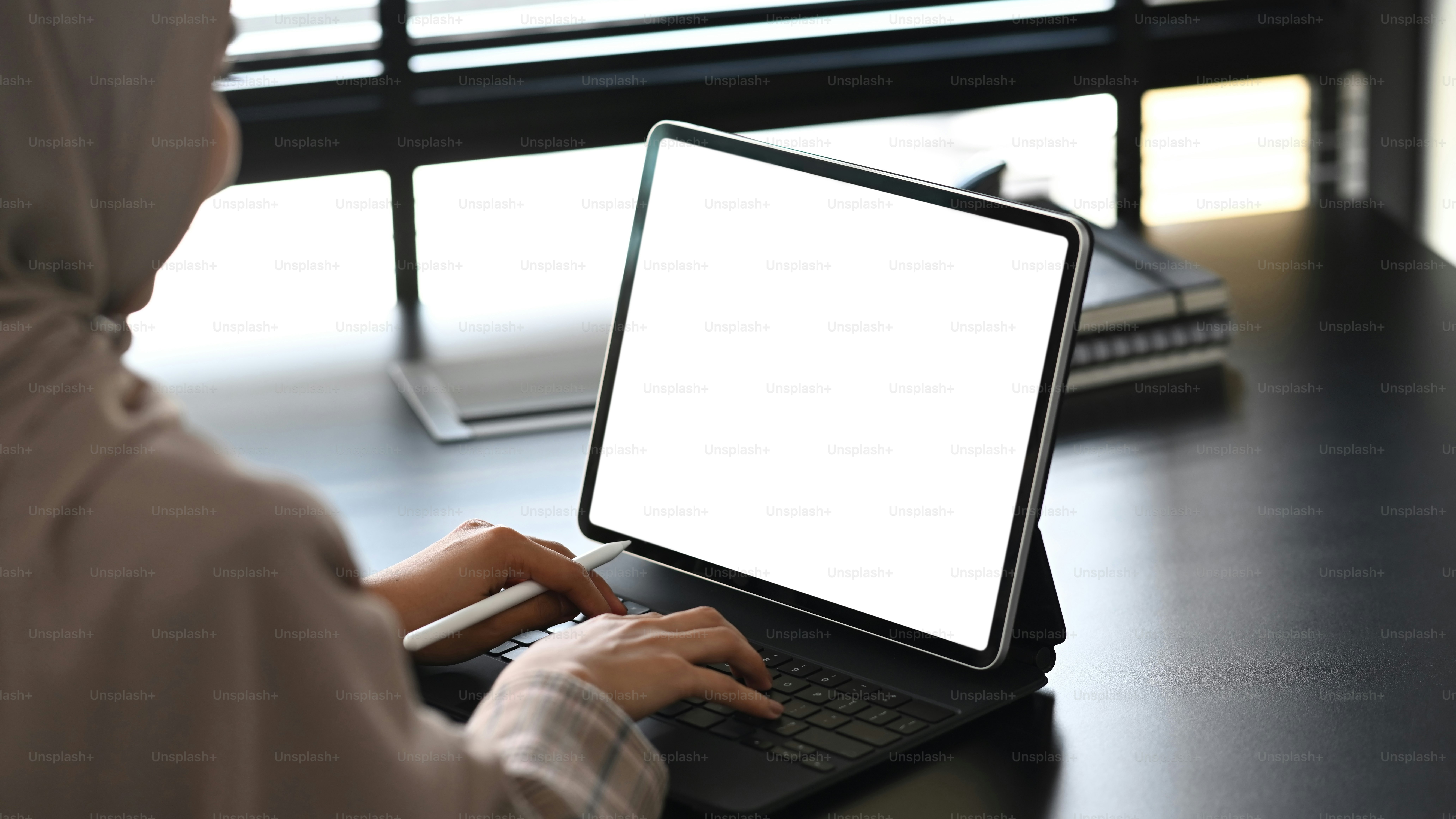 The backside of business muslim woman working on blank screen computer tablet.