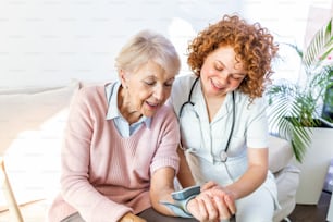 집에서 노인 여성의 혈압을 측정하는 간병인. 요양원의 침대에서 행복한 노인 여성의 혈압을 측정하는 친절한 간병인.
