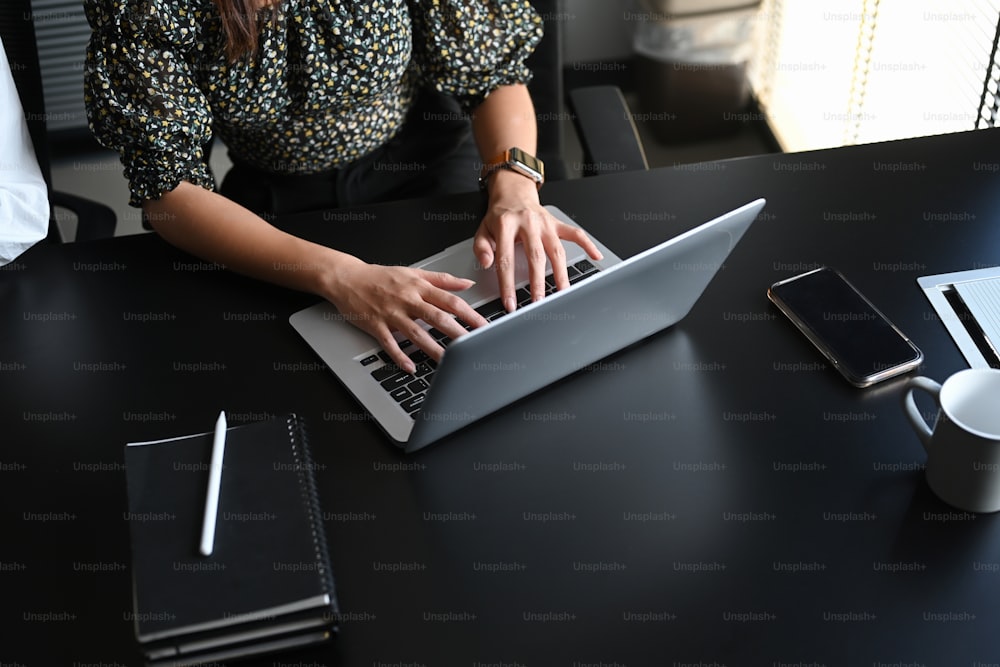 Foto cortada de uma jovem empresária confiante digitando e-mail no laptop do computador no escritório moderno.