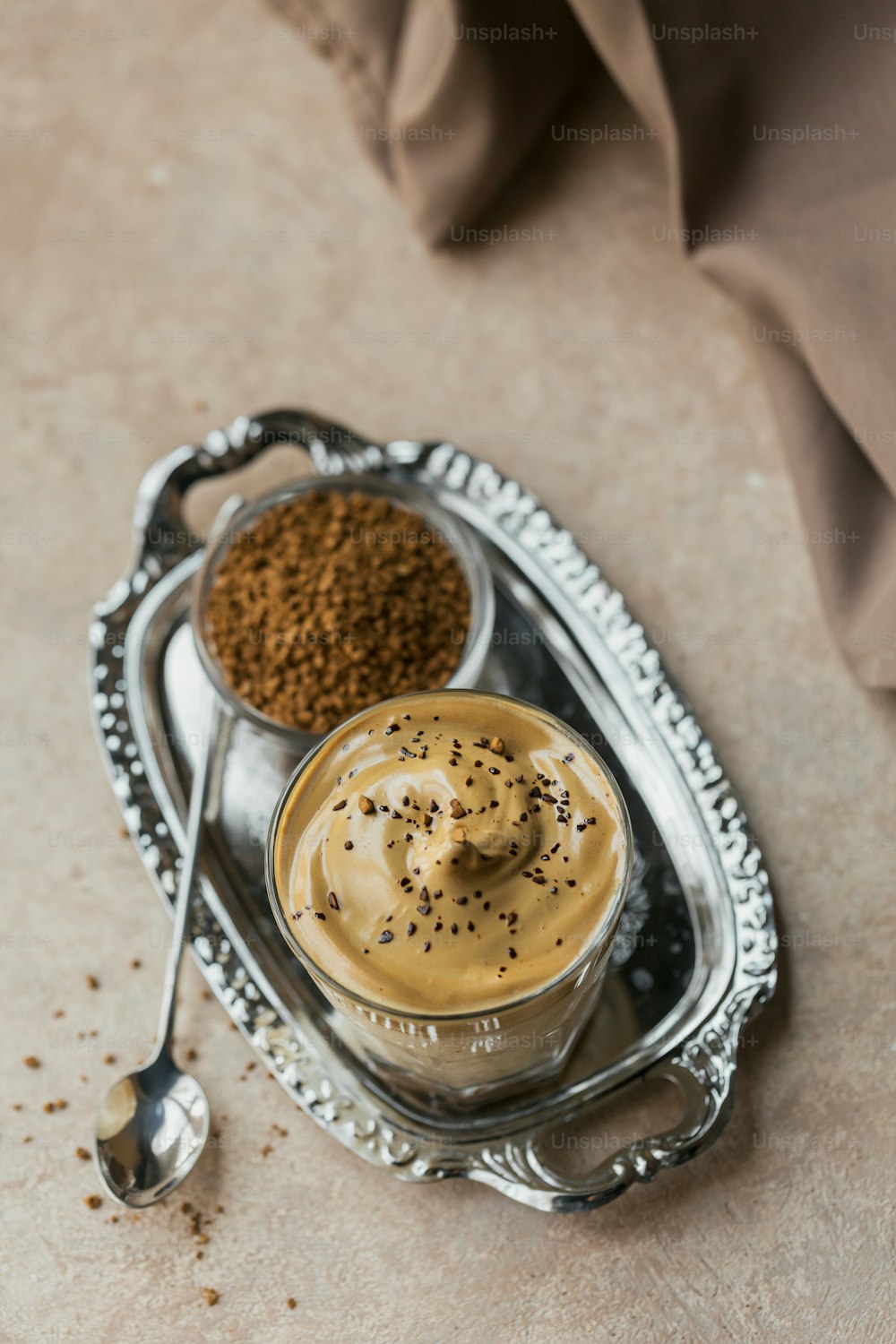 Verre de café Dalgona glacé, un café fouetté crémeux moelleux et du lait sur fond beige clair.