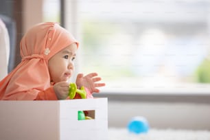 Muslim Baby plays with colorful toys in the living room.