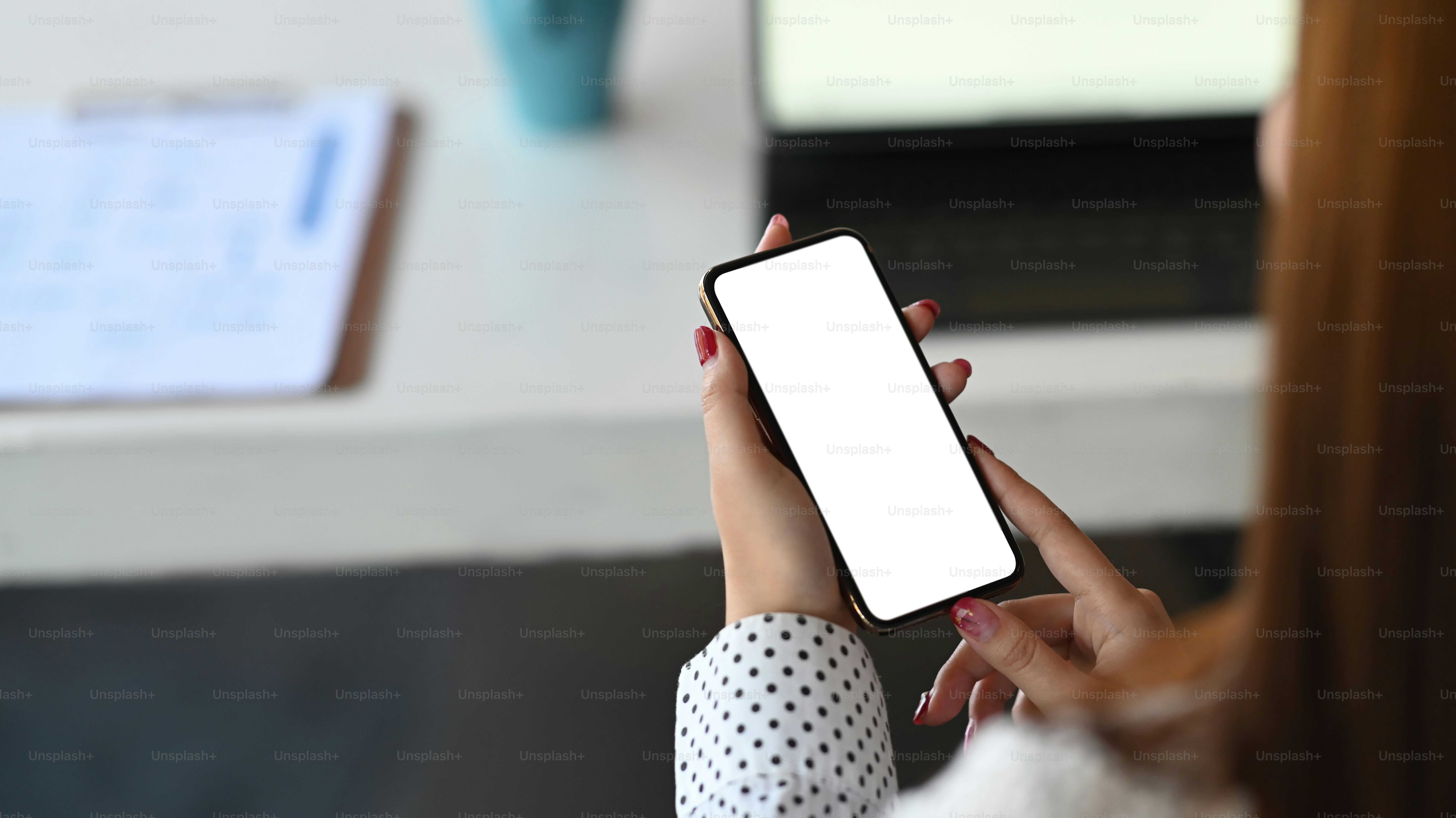 Imagen de las manos de la mujer sosteniendo un teléfono celular negro con una pantalla blanca en blanco. Pantalla blanca en blanco para montaje gráfico.