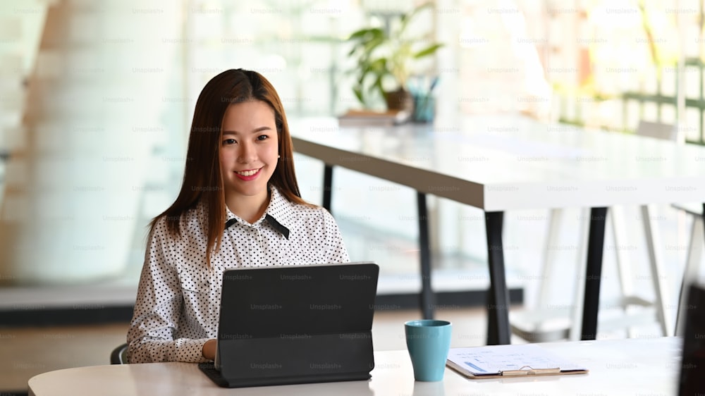 Una giovane donna d'affari che lavora o utilizza il tablet del computer cercando informazioni online sul suo posto di lavoro.