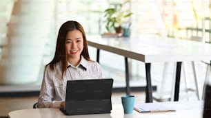 Una joven empresaria que trabaja o usa una tableta de computadora que busca información en línea en su lugar de trabajo.