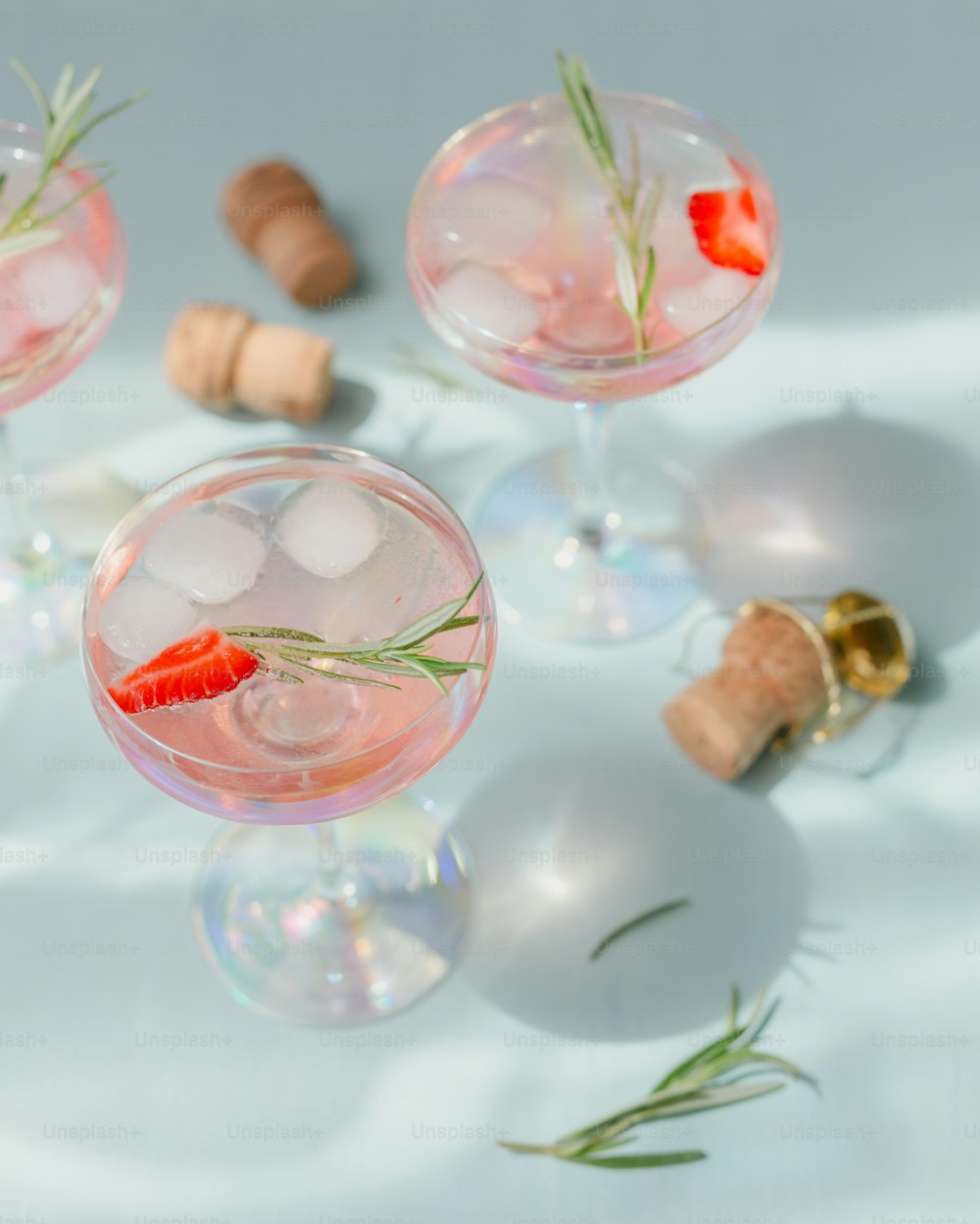イチゴのカクテルやモクテルのグラス、水色の背景に砕いた氷とスパークリングウォーターとさわやかな夏の飲み物。飲料の写真撮影。