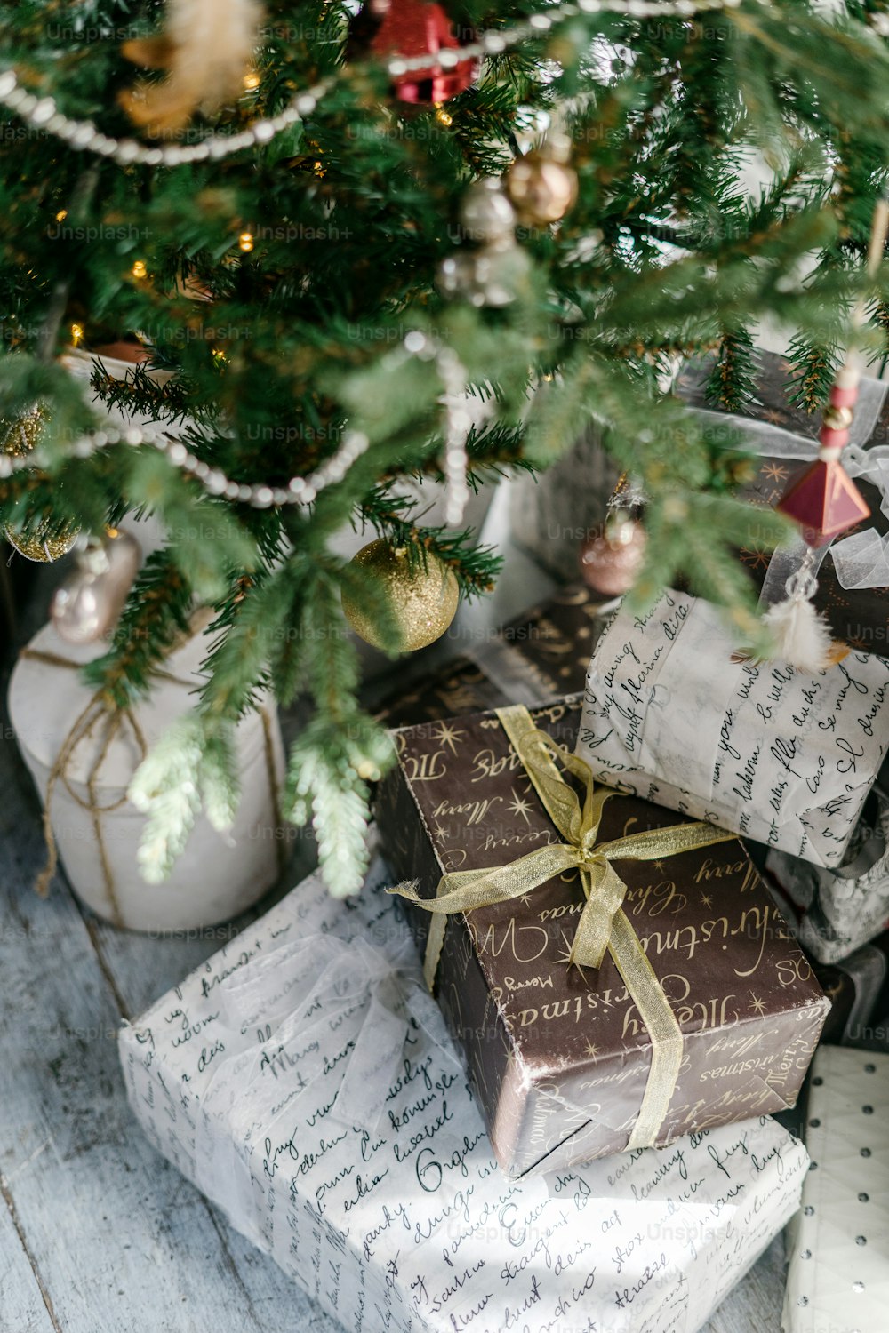 Vertical photo of new year present boxes under decorated christmas tree. Element of cozy interior with simple and craft package. Concept of preparation for december holidays